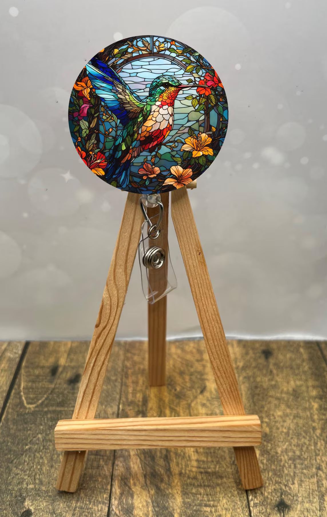 Colorful hummingbird badge pulls displayed on a wooden easel with floral details, perfect for brightening up uniforms.