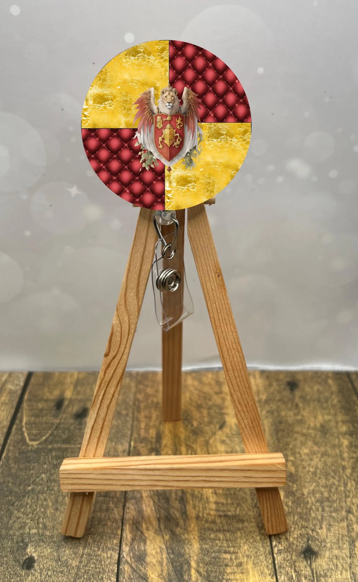 Gryffindor badge pull with glitter displayed on an easel with red and gold design.