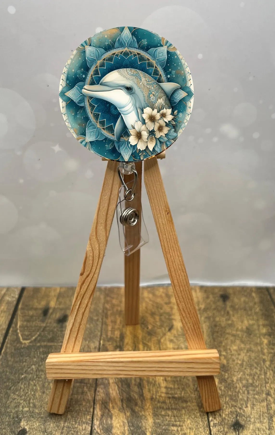 Dolphin badge pull with glitter showcased on display, featuring a playful dolphin design and floral accents.