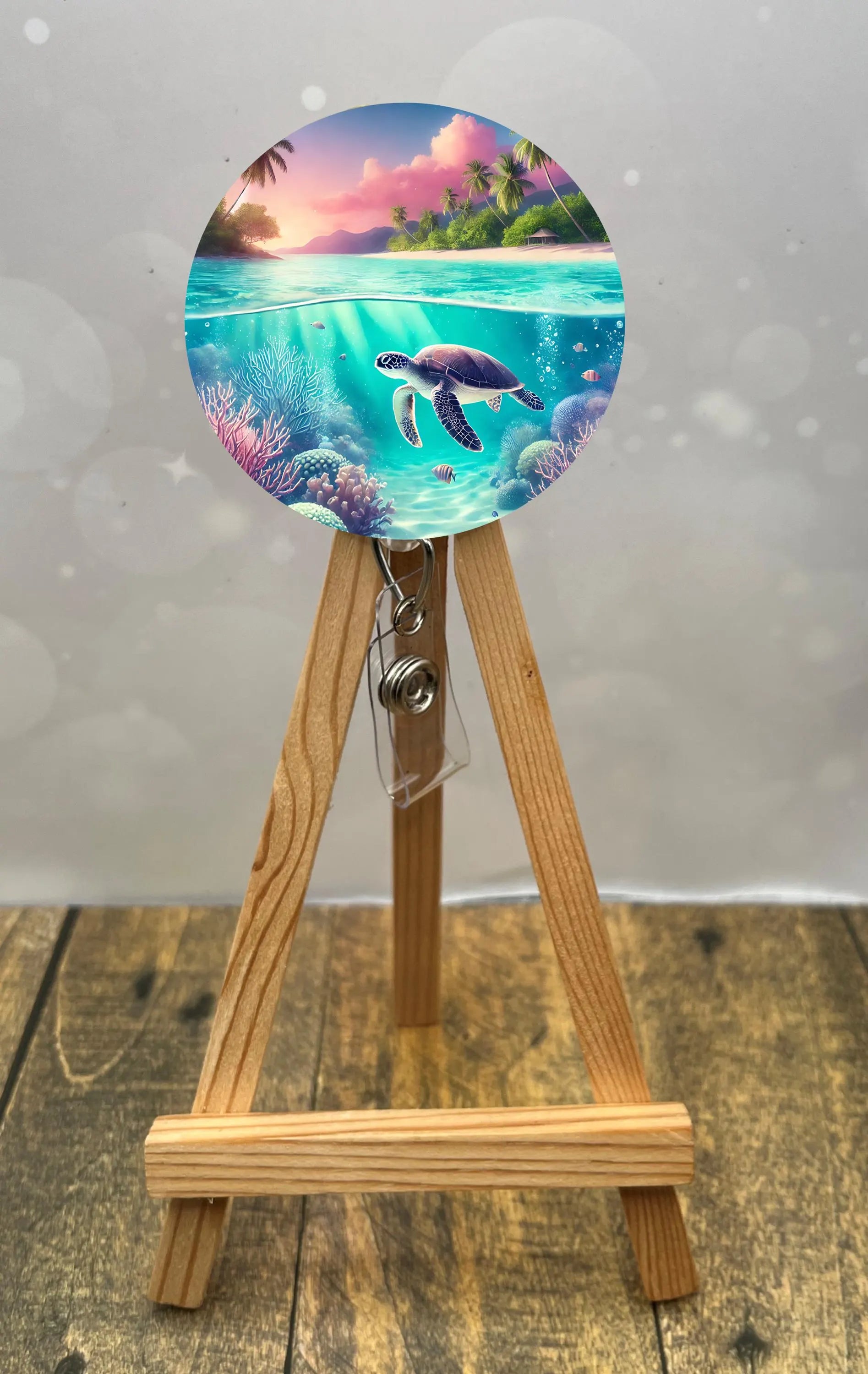 Sea turtle badge pulls displayed on an easel, featuring a colorful ocean scene with coral and palm trees.