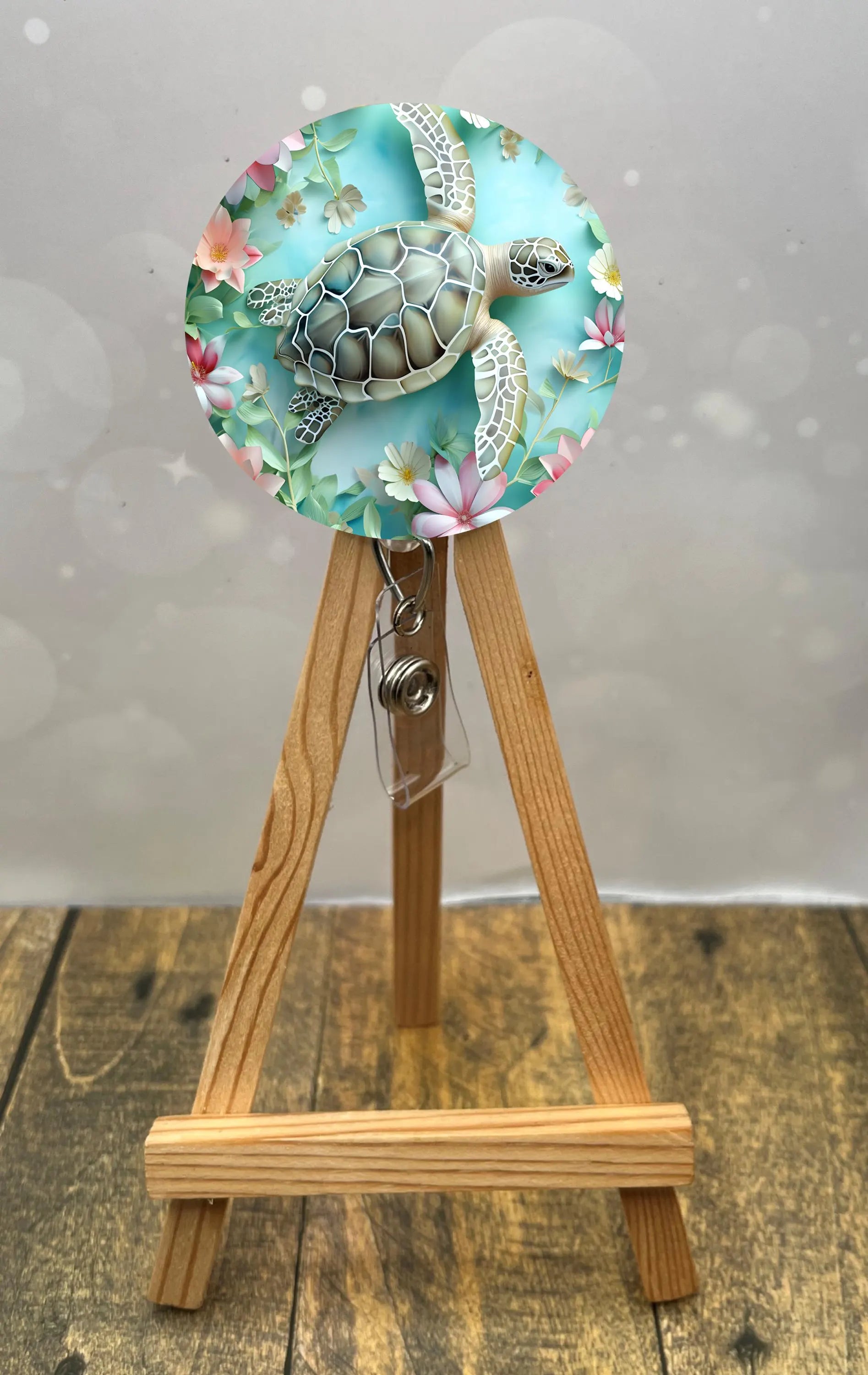 Sea turtle badge pulls featuring a vibrant design with floral patterns, displayed on a wooden easel.