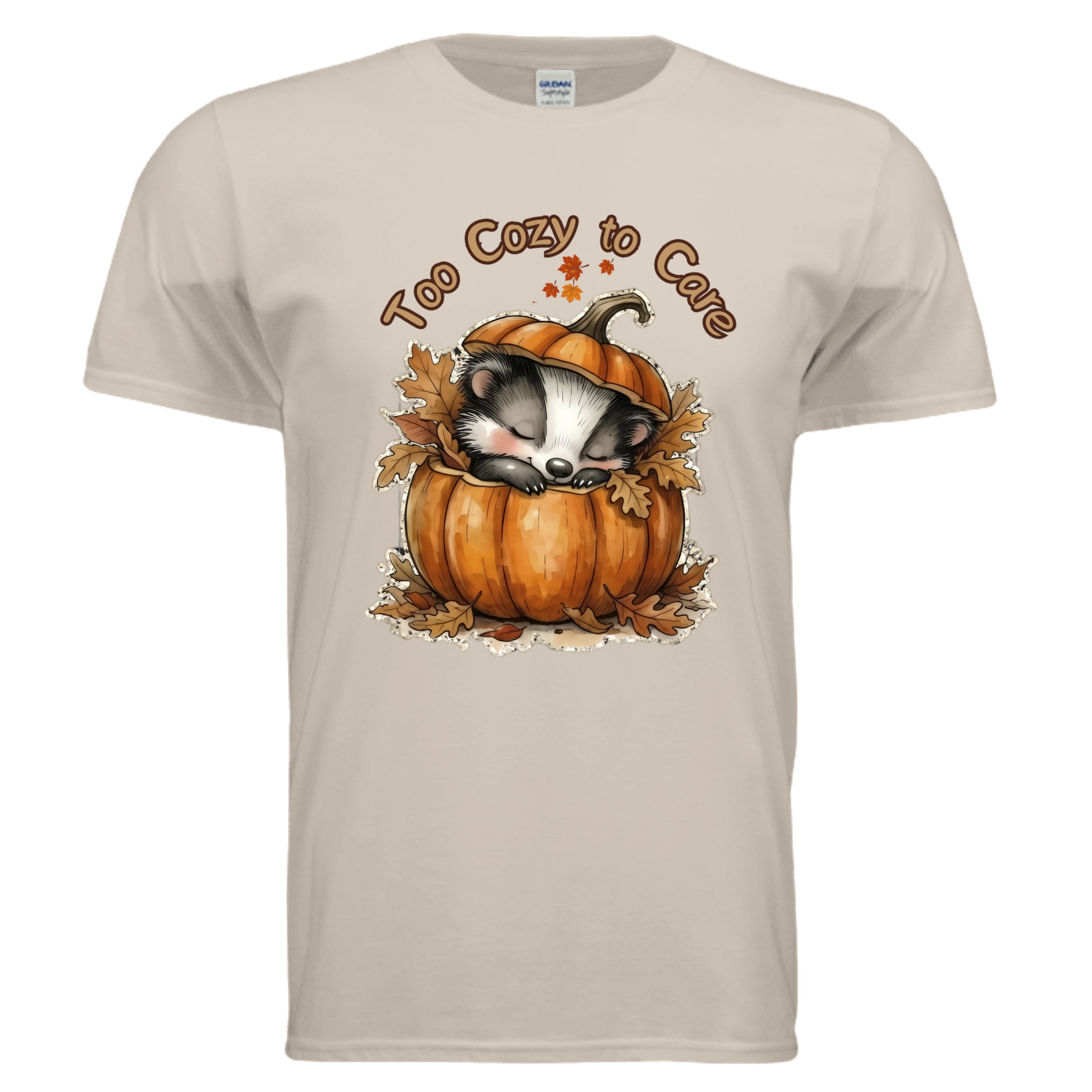 Too Cozy to Care graphic tee featuring a sleeping badger in a pumpkin surrounded by leaves, perfect fall graphic tee in sand color.