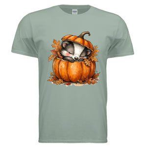Cozy Badger graphic tee featuring a badger sleeping in a pumpkin with autumn leaves on a sage background.